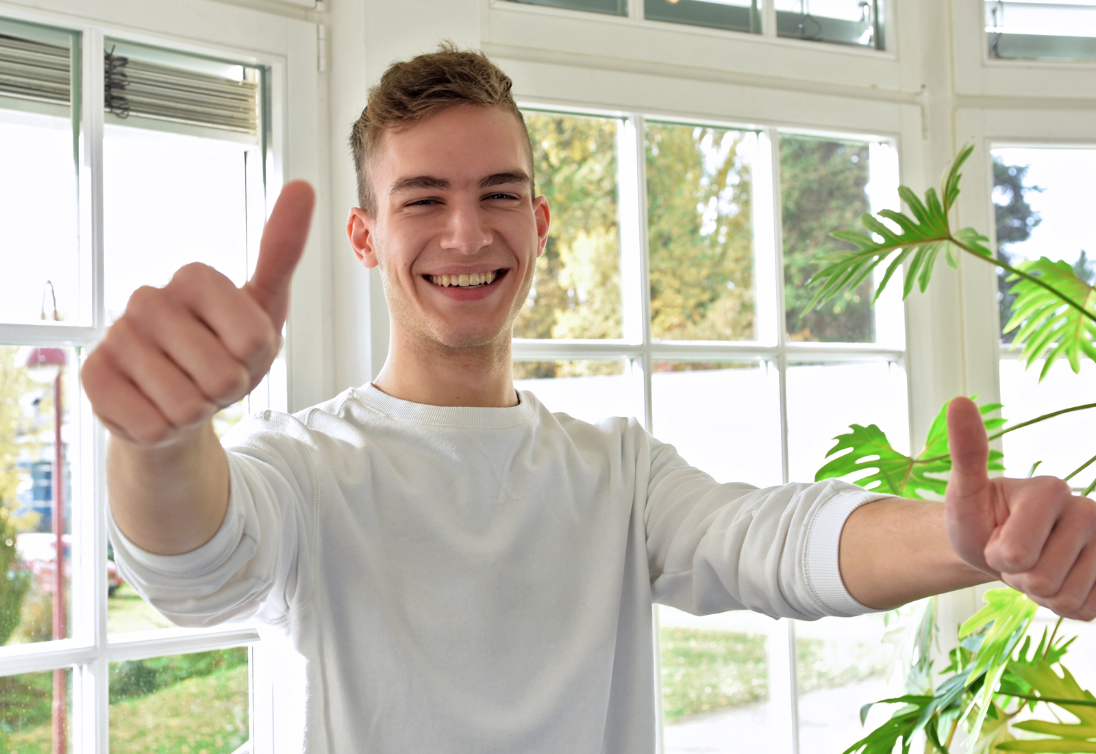 Foto von einem lachenden jungen Mann beide Daumen nach oben hebt